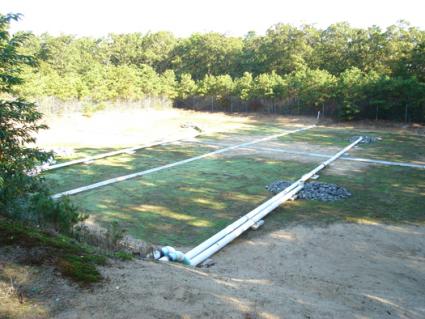 Mashpee Commons WWTF effluent recharge locfield showing a series of pipes horizontal on the groud - surrounded by trees